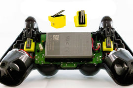 Geöffneter PS4 Controller mit eingesetzten gelben Smarttrigger Modulen und zwei weiteren Ersatzteilen